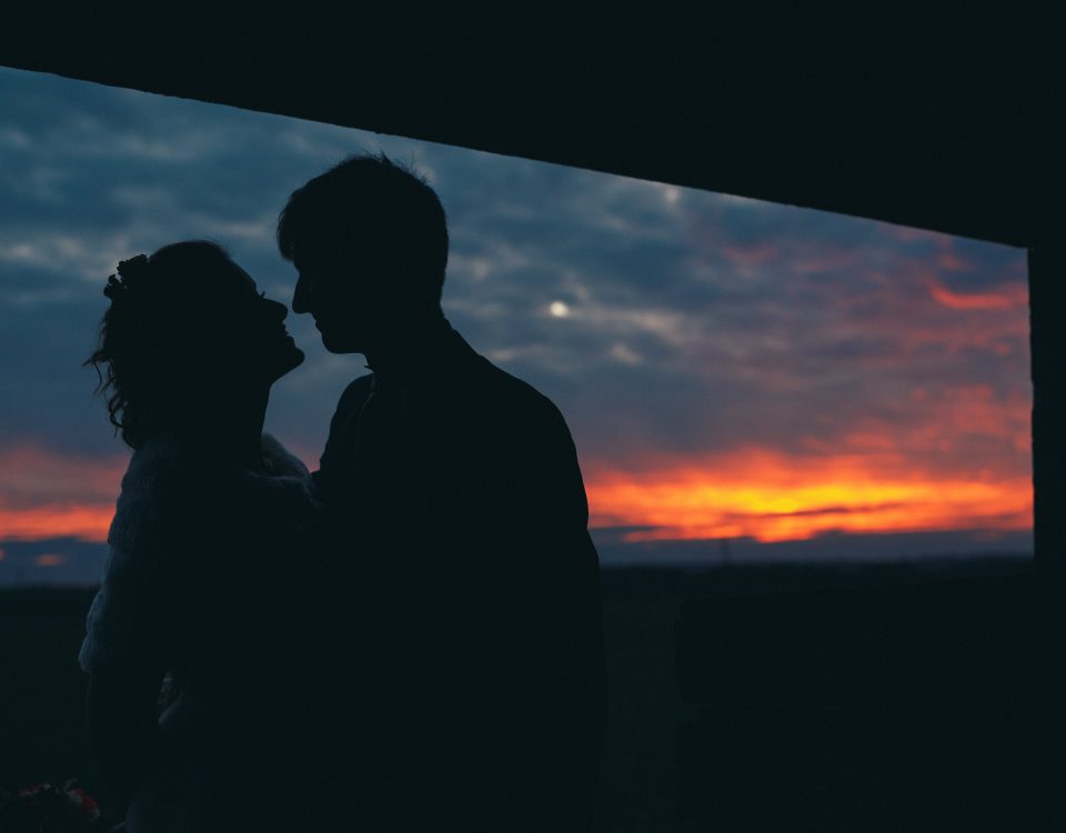 newlyweds silhouette kissing with sunset near barn rustic winter wedding photography